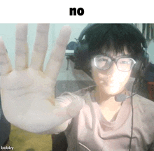 a man wearing glasses and headphones is making a stop gesture with his hand