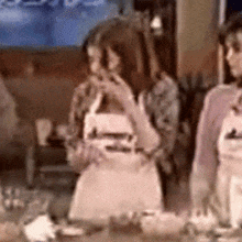 a woman wearing an apron that says ' a ' on it sits at a table