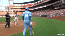 a baseball player with the number 14 on his back stands on the field