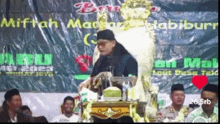 a man sitting on a throne giving a speech in front of a group of people .
