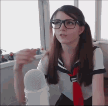 a girl with glasses and a red tie is standing in front of a microphone