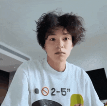 a young man wearing a white t-shirt with the numbers 2-5 on it