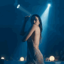 a woman in a very revealing dress is dancing in front of a blue light