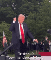 a man in a suit and tie is dancing in front of a sign that says tristan jr
