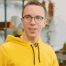 a man wearing glasses and a yellow hoodie