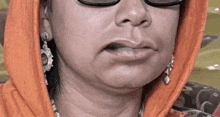 a close up of a woman 's face with glasses and a scarf around her head .