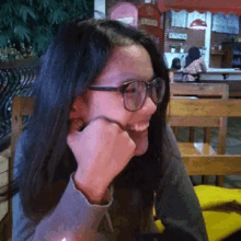 a woman wearing glasses is smiling in front of a chicken restaurant