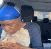 a man wearing a blue headband eating a sandwich in a car