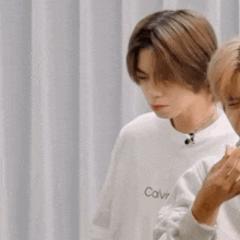 a man wearing a white calvin klein sweatshirt is making a funny face
