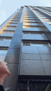 a man looking up at a tall building with many windows