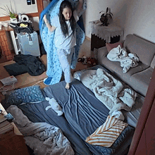 a woman in pajamas is standing on a bed with a blue blanket