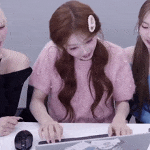 a woman in a pink shirt is using a laptop computer
