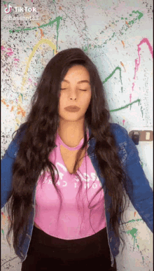a woman with long hair wearing a pink shirt and a blue jacket