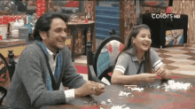 a man and a woman are sitting at a table and laughing