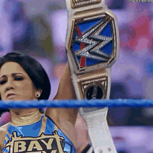 a woman in a wrestling ring holds up a wwe title belt