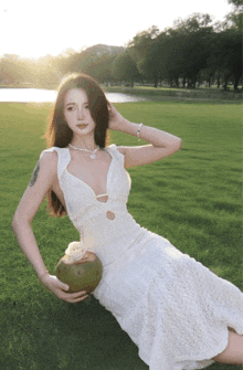 a woman in a white dress is holding a coconut in her hand