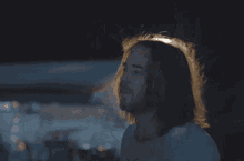 a woman in a white shirt stands in the dark