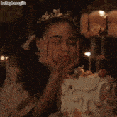 a girl with a tiara on her head is blowing out a candle on a cake