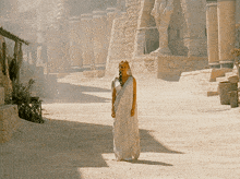 a woman in a white dress is standing in front of a building