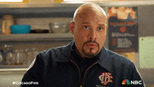 a bald man with a beard is wearing a jacket that says ' chicago fire ' on it