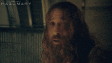 a man with long hair and a beard is in front of a project hailmary poster