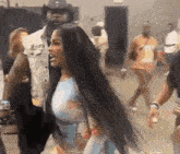 a woman with long black hair is standing in a crowd .