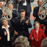 a woman in a red jacket is clapping in front of a band