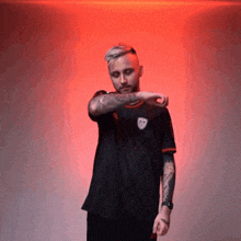 a man with a tattoo on his arm is wearing a black shirt with the letter t on it