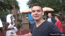 a man in a blue shirt is standing in front of a group of people in a park .