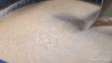 a wooden spoon is stirring a mixture in a pot .