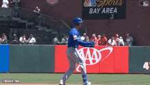 a baseball player stands on a field in front of a sports bay area sign