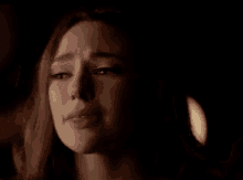 a close up of a woman 's face in a dark room with a light behind her .
