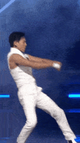 a man in white pants and a white shirt is dancing on a stage .