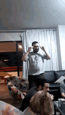 a man wearing a gray shirt with a horse on it is standing next to a woman on a couch