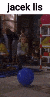 a child is playing with a blue ball in a classroom with the words jacek lis on the top