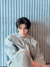 a young man wearing a denim jacket sits on the floor