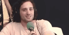 a man wearing headphones and holding a green microphone .