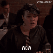 a woman sitting at a table with a glass of wine and the word wow on her face