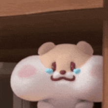 a stuffed animal is sitting under a table with tears running down its face .