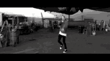 a black and white photo of a man dancing in front of a plane