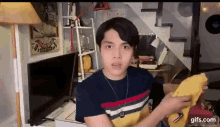 a young man is holding a piece of paper in front of a tv .