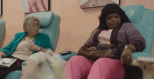 two women are sitting in chairs in a nail salon and one has a purse on her lap .