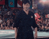 a man in a karate uniform stands in front of a crowd of people