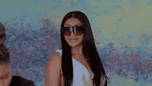 a woman wearing sunglasses and a white dress is smiling .