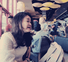 a woman sitting at a table in a restaurant with a sign that says ' ovo '