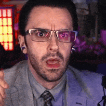 a man wearing glasses and a suit is making a face