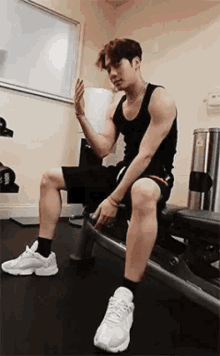 a man is sitting on a bench in a gym with a dumbbell in his hand .