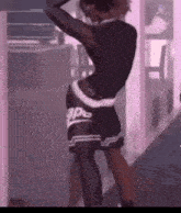 a man in a black shirt and black shorts is standing in a room with his hands on his head .
