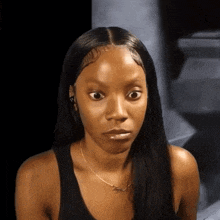 a woman wearing a black tank top and a necklace that says ' jesus ' on it
