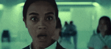a woman is looking at the camera with a surprised look on her face in a hallway .